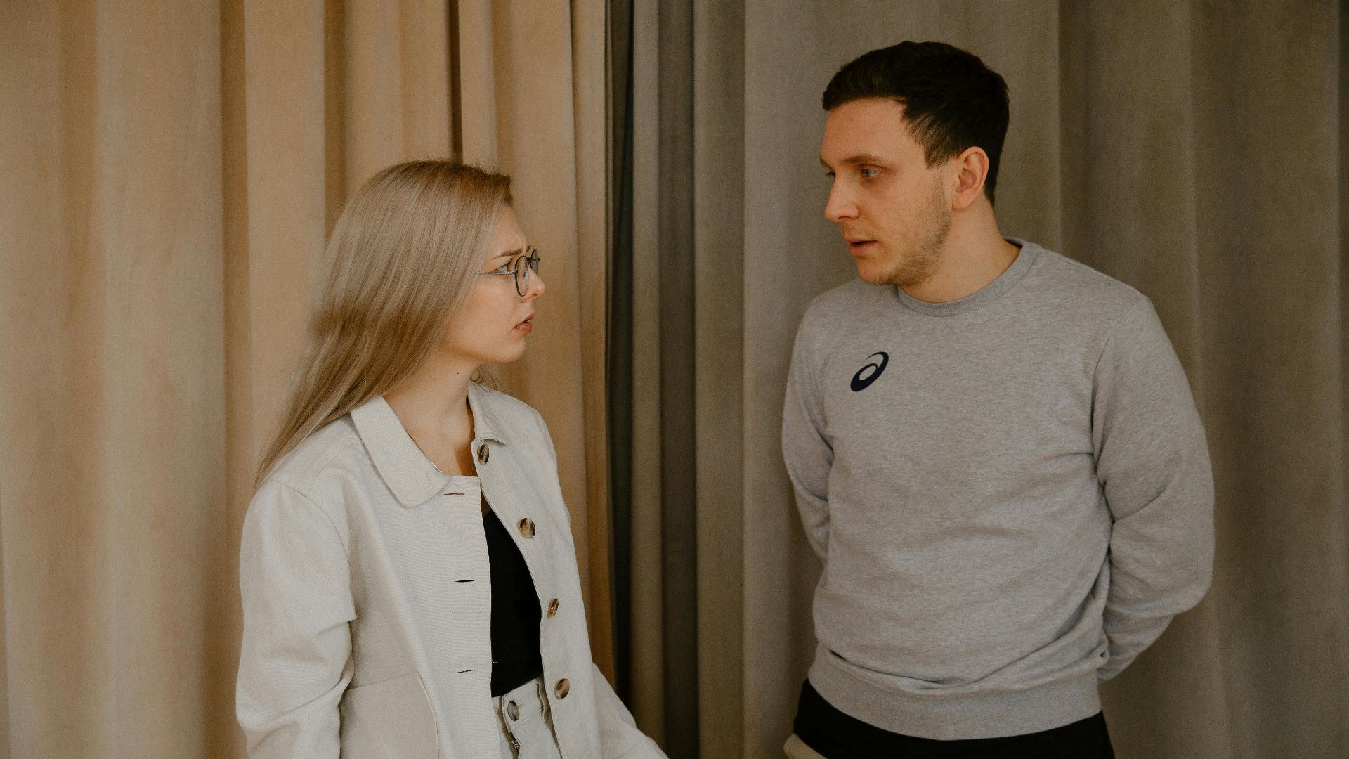 Man and woman having a serious conversation indoors, focused expressions.