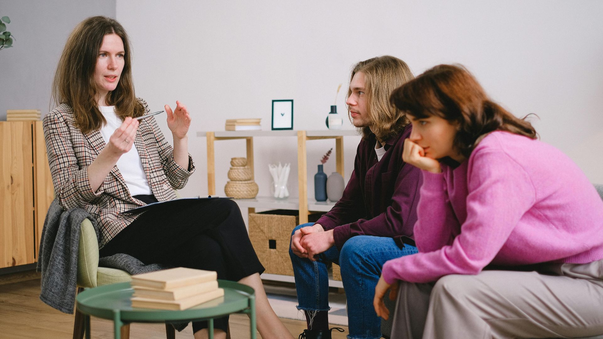 A counselor having a discussion with two students in an inviting, modern interior space.
