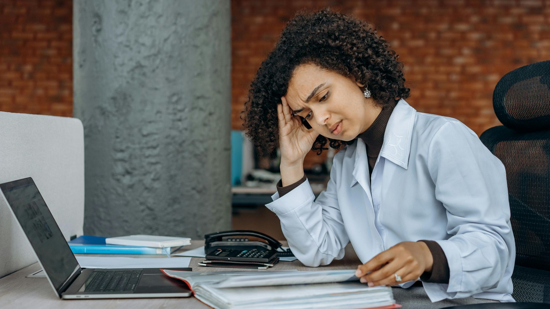 Businesswoman experiencing fatigue while working on financial paperwork at her desk.