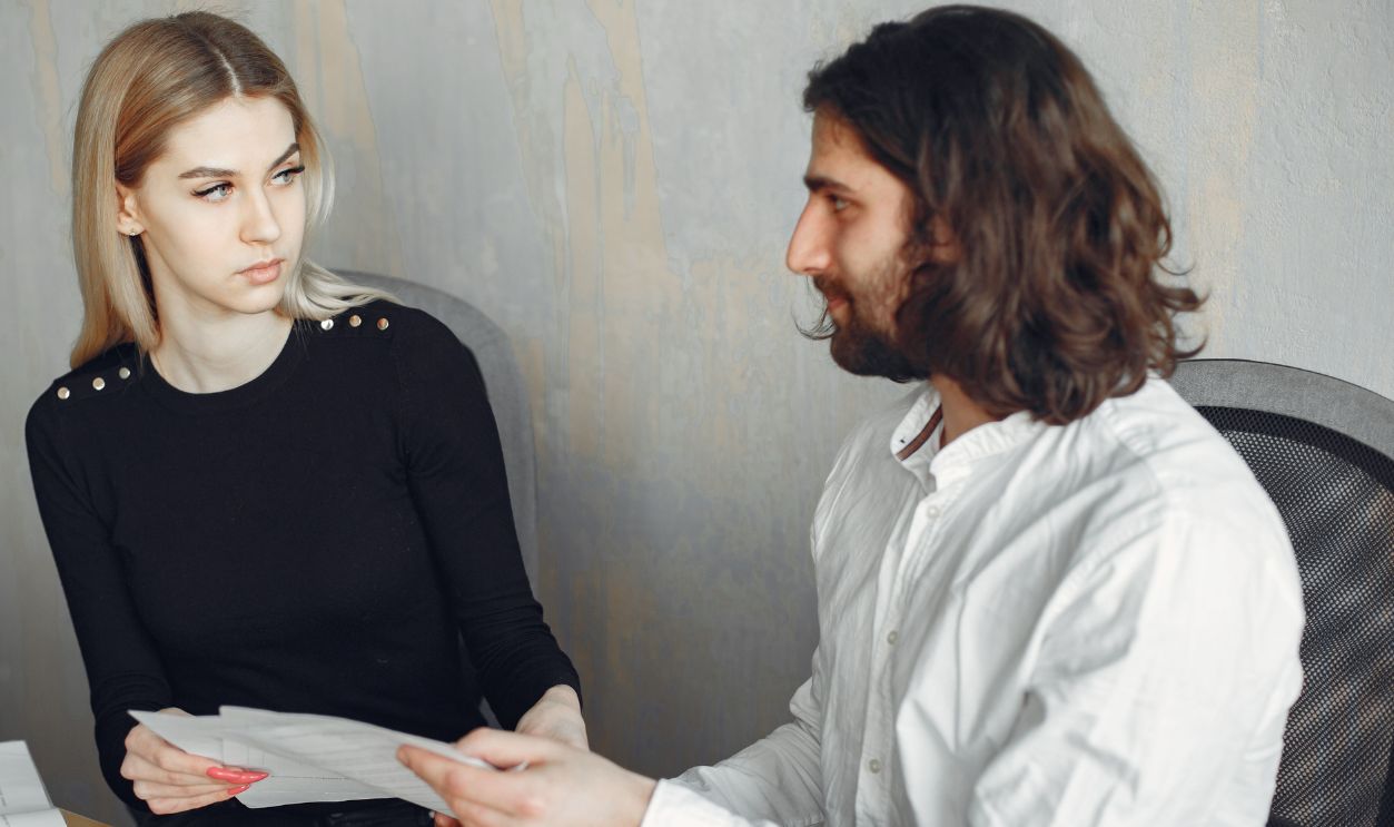 Two colleagues engaged in a focused discussion at the office, sharing documents