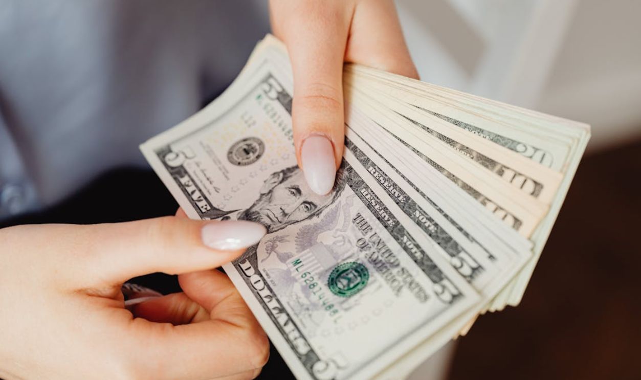 Hands count US dollar bills, showcasing finance and cash handling concepts