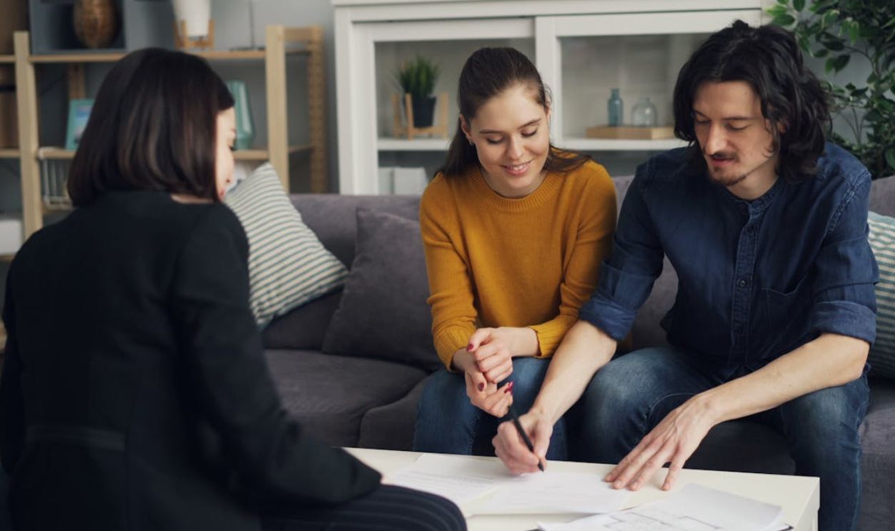 Three young adults working together at a home setting, signing documents