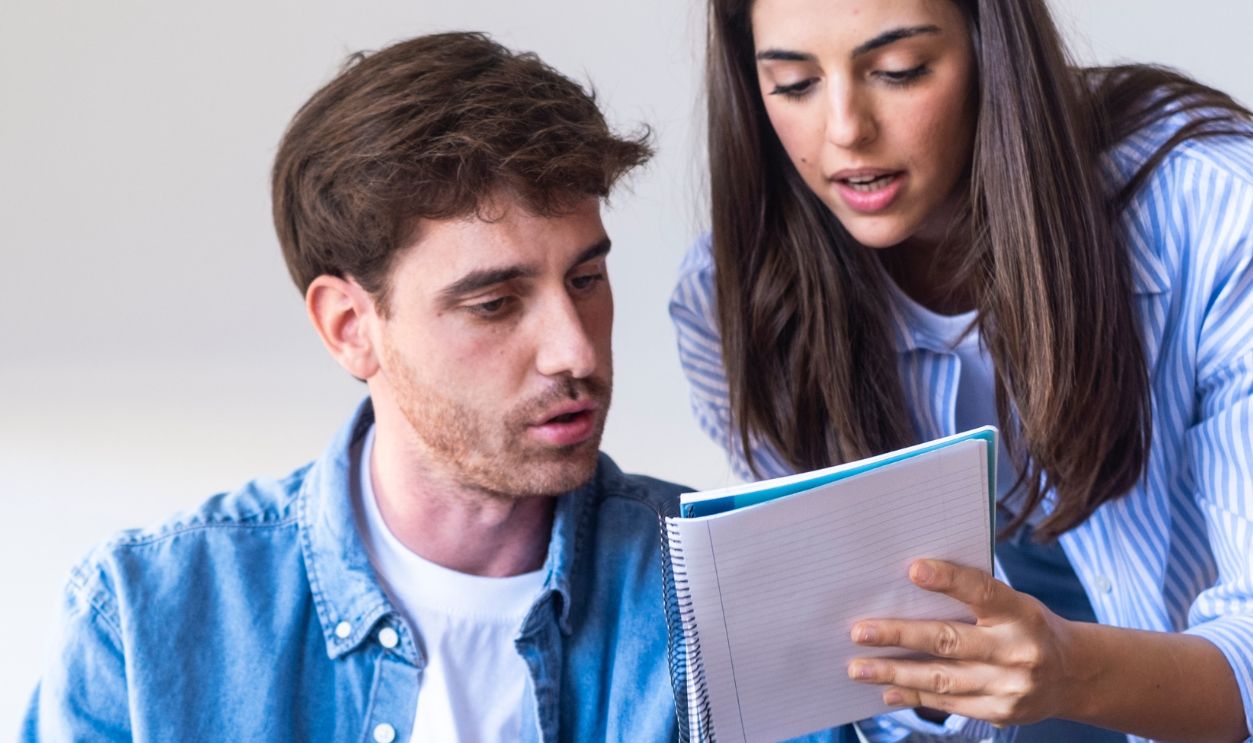 Young couple sitting at home reviewing documents and laptop together, focused on managing household expenses, bills, or investments. Serious expressions reflect financial planning, budgeting, and life