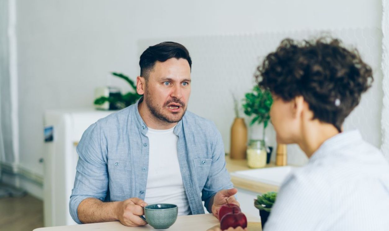 Couple having a serious conversation at the kitchen table with coffee cups