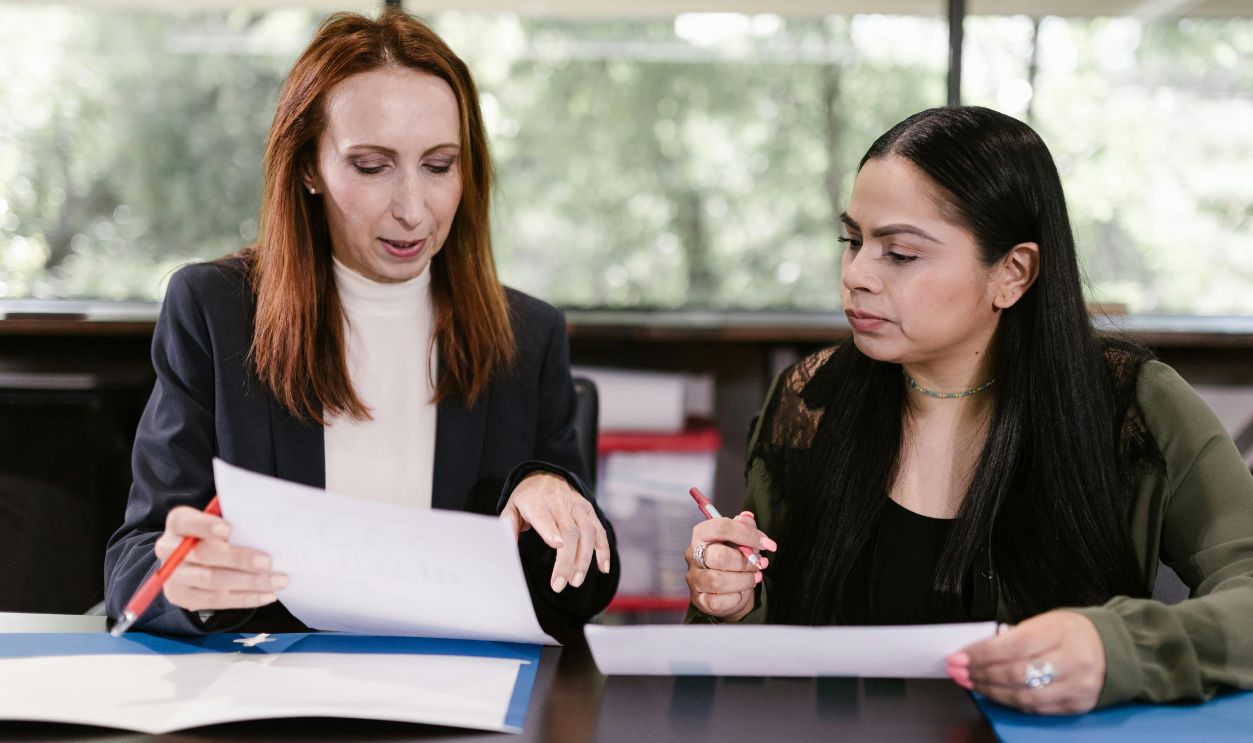 Two professional women reviewing documents in a well-lit office 