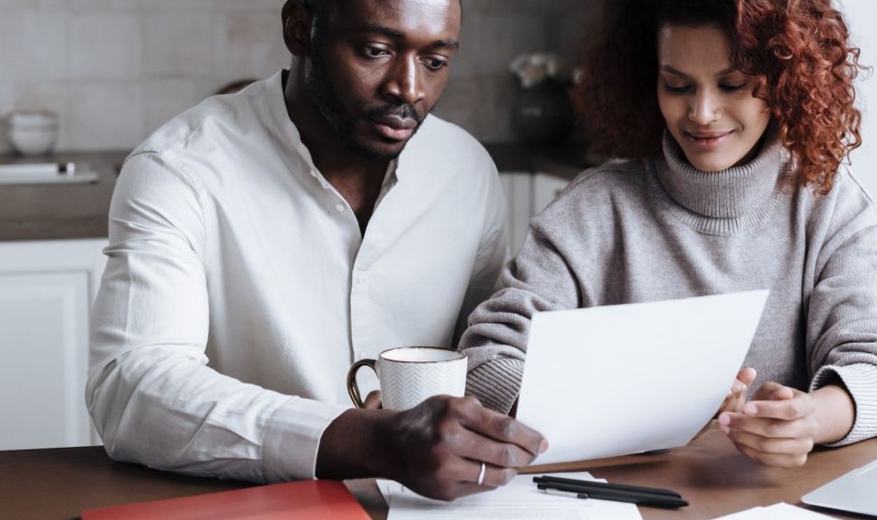 A couple reviews paperwork at a kitchen table, embodying teamwork and collaboration