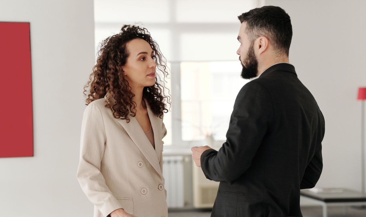 Two professionals engaged in a discussion in a bright, modern office 