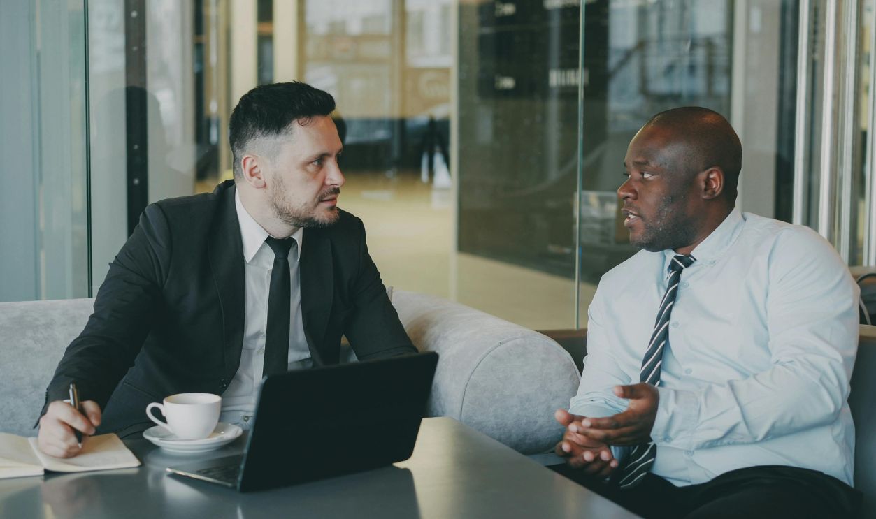Two businessmen discussing at a cafe with a laptop 
