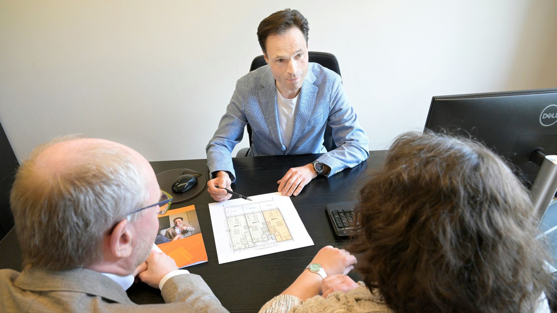 Consultant explains plans to a couple during a business meeting.