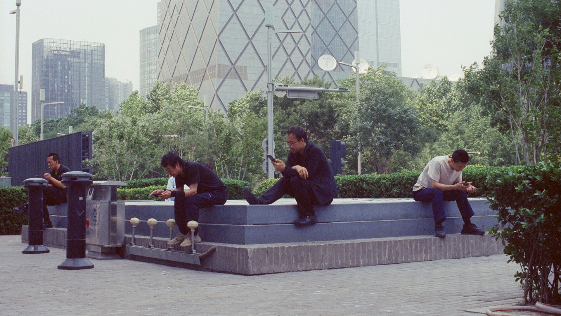 People sitting on a bench in a modern city park.