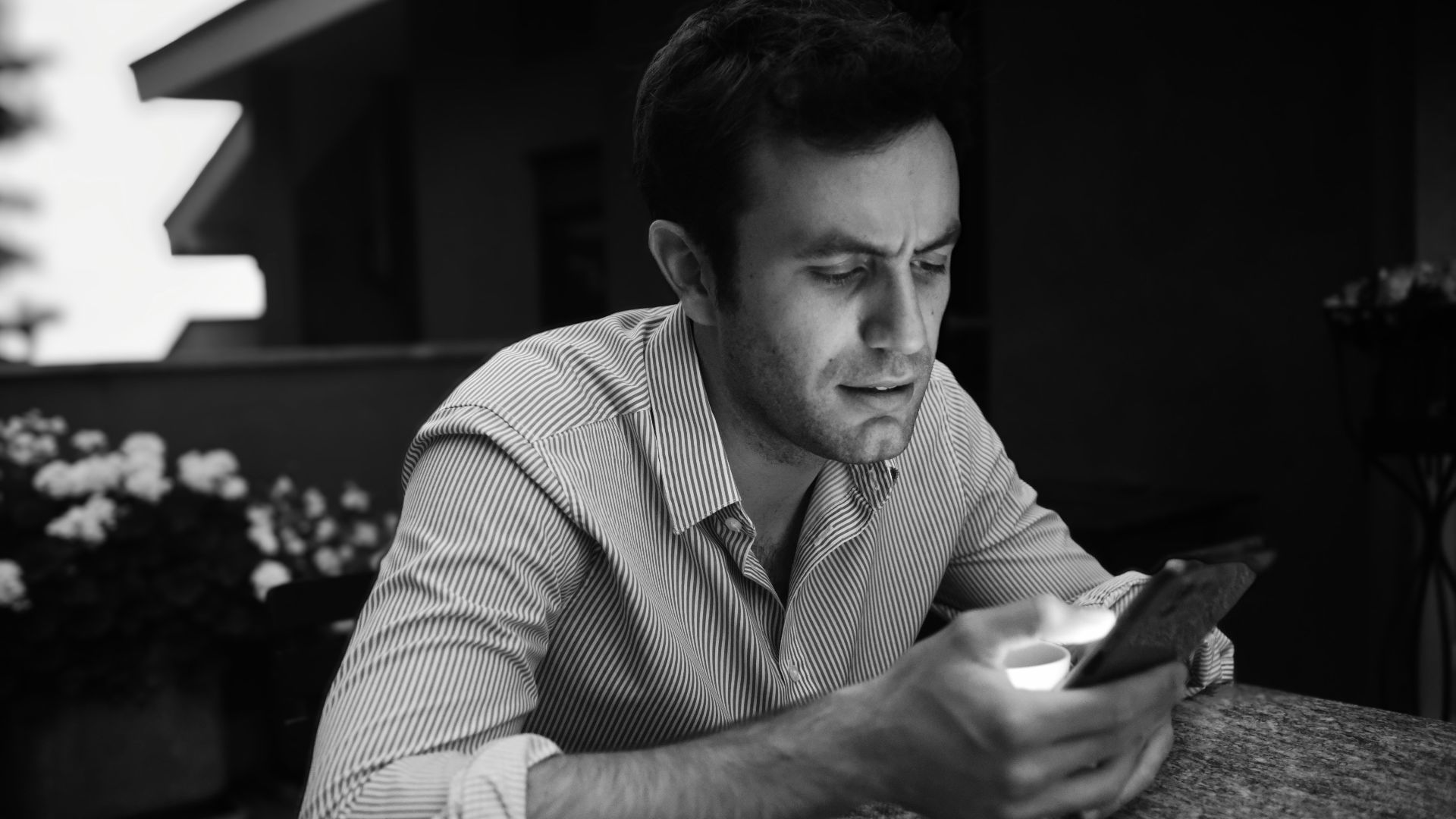 a man sitting at a table looking at a cell phone