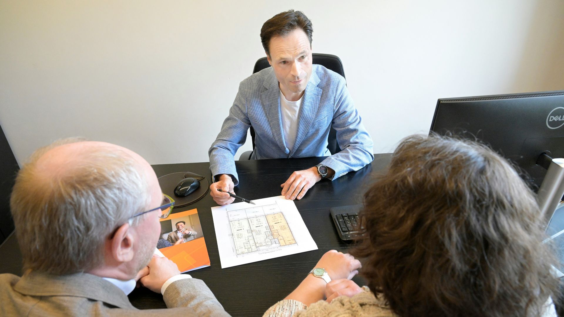Consultant explains plans to a couple during a business meeting.