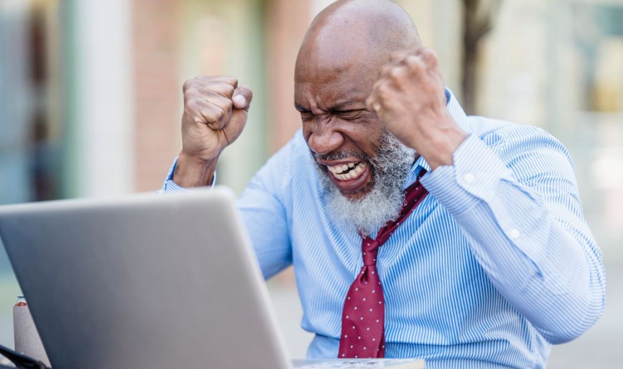 African American businessman showing frustration working on a laptop outdoors.