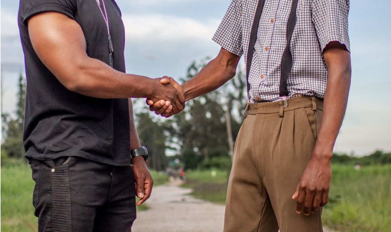 Two men shaking hands outdoors in Lusaka, Zambia. Captures cooperation and agreement