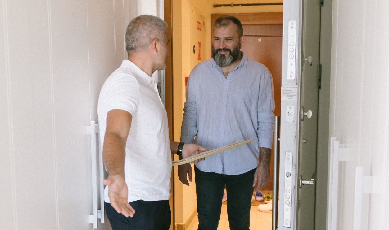 Two men converse at a doorway in an Istanbul apartment, emphasizing hospitality and communication