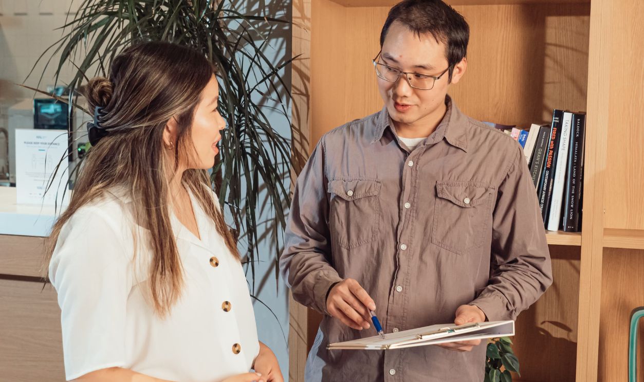 Two colleagues discussing work in a modern office setting