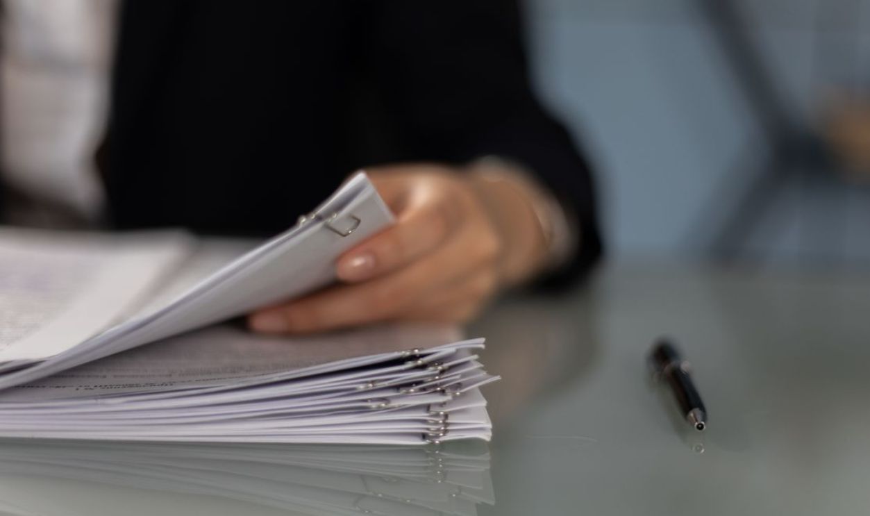 Close-up of a professional organizing a stack of documents on a desk