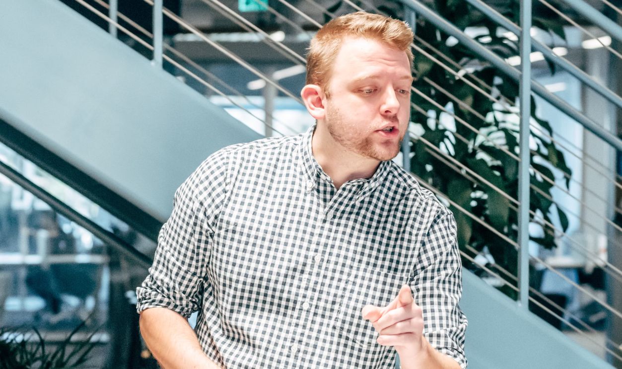 A man in a checkered shirt discussing ideas in a modern office workspace
