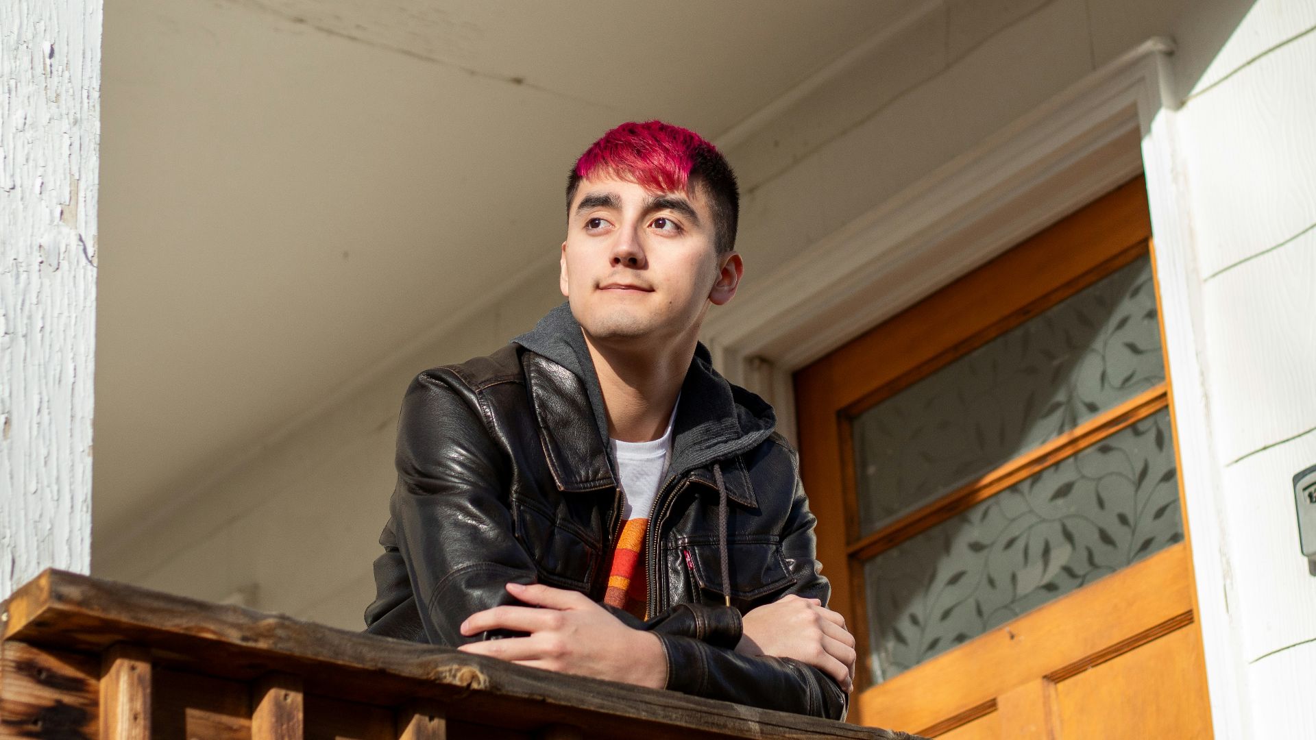 a man with pink hair standing on a porch