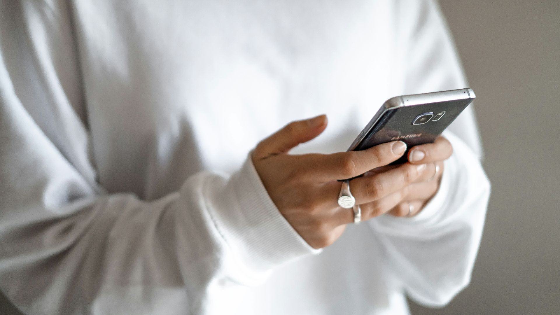 person in white long sleeve shirt holding black smartphone