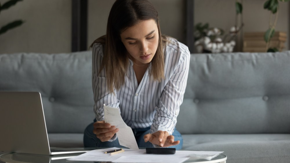 Young woman wife work with bills invoices at home