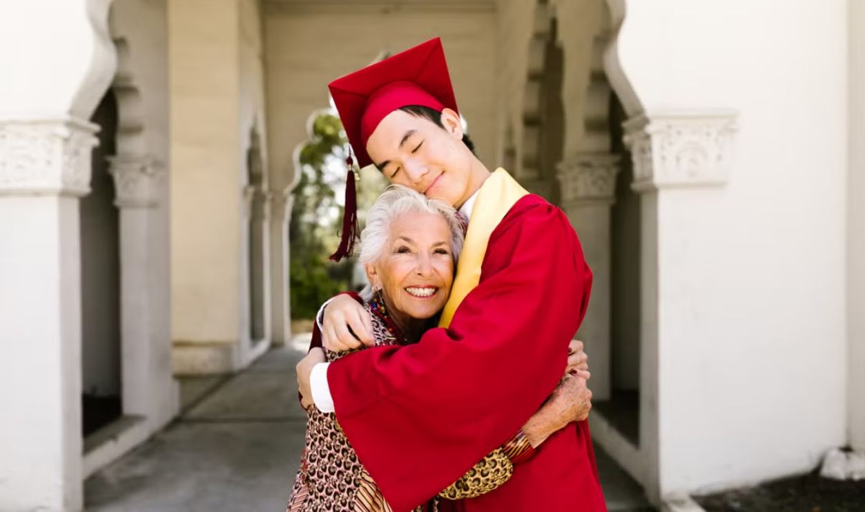 A graduate embraces his grandmother, capturing a heartfelt moment of achievement and love