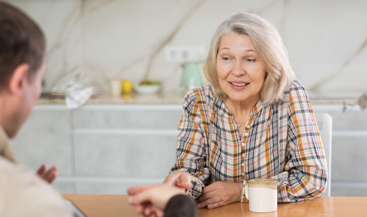 Male insurance agent tells an elderly woman the terms of an insurance contract. Offers to sign documents