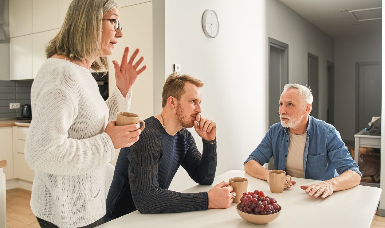 Emotional family of senior parents and son communicating at kitchen