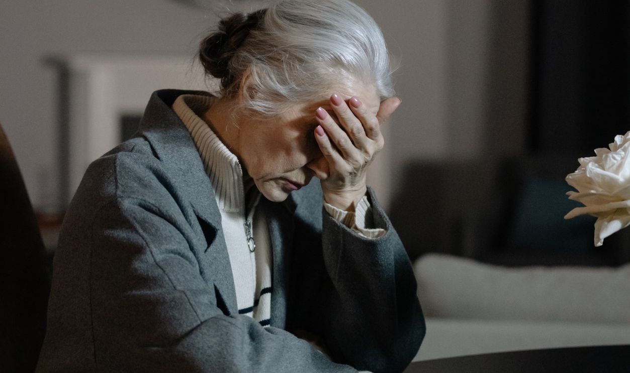 Senior woman grieving indoors at home, expressing deep emotion and loss