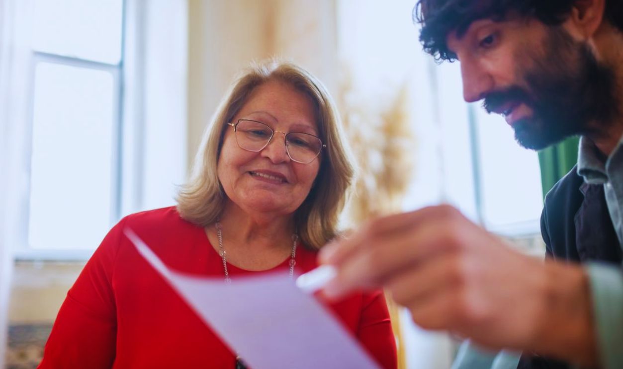 Elderly woman and bearded man in a consultation meeting reviewing documents indoors
