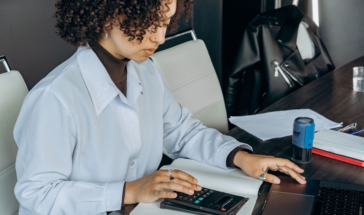 Young woman in office using a calculator for financial calculations.