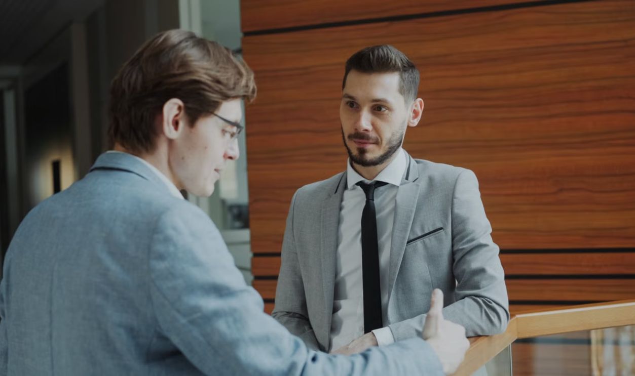 Two male professionals engaged in conversation in a modern office setting
