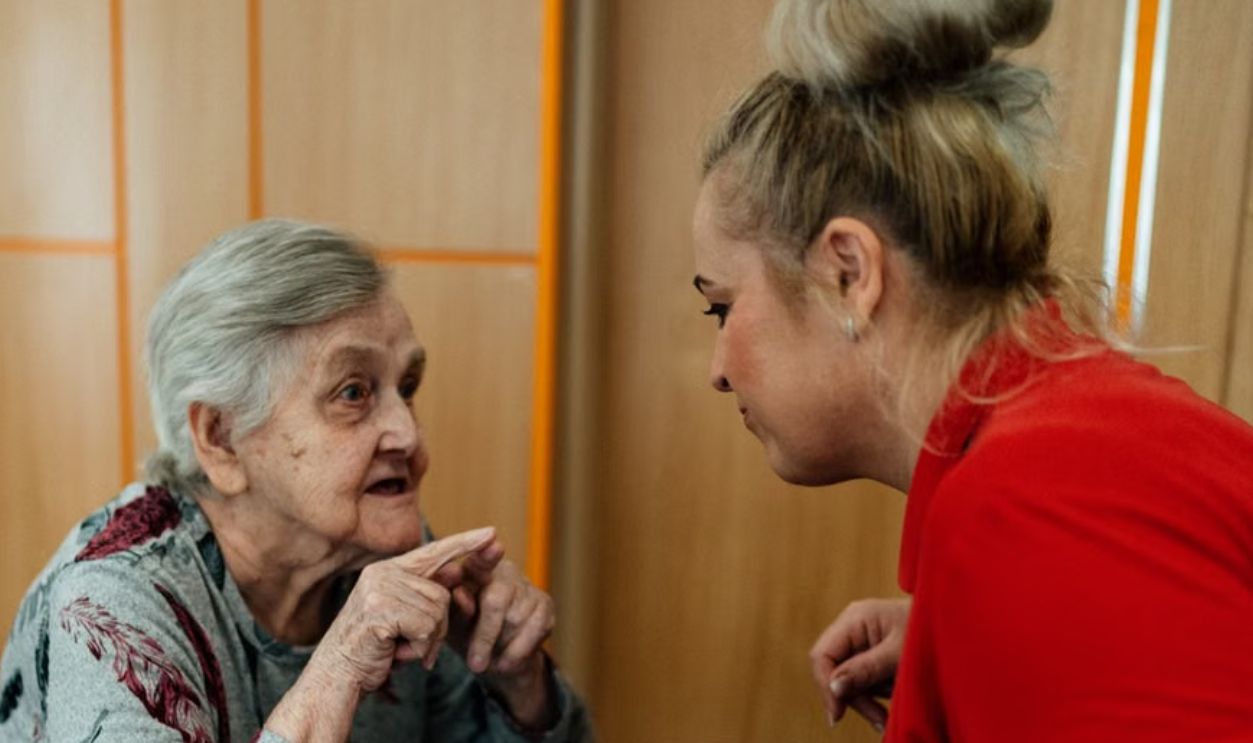 Elderly woman and caregiver in conversation inside a room in Karvina, Cesko