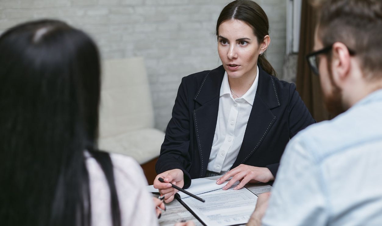 Three colleagues engaged in a business meeting discussing documents at a table indoors