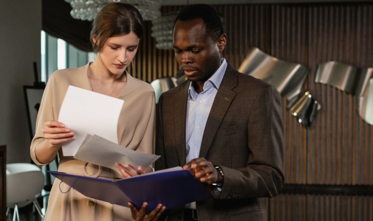 Two professionals discussing documents in a stylish office environment, exhibiting teamwork.
