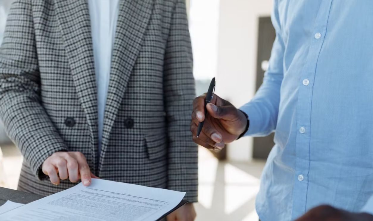 Two professionals reviewing business documents and discussing details in an office setting