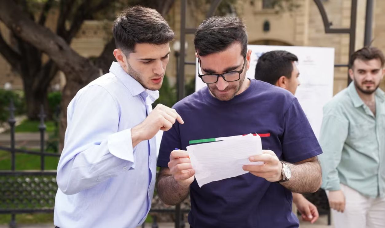 A group of adults engaged in discussion, analyzing documents outdoors in a park setting