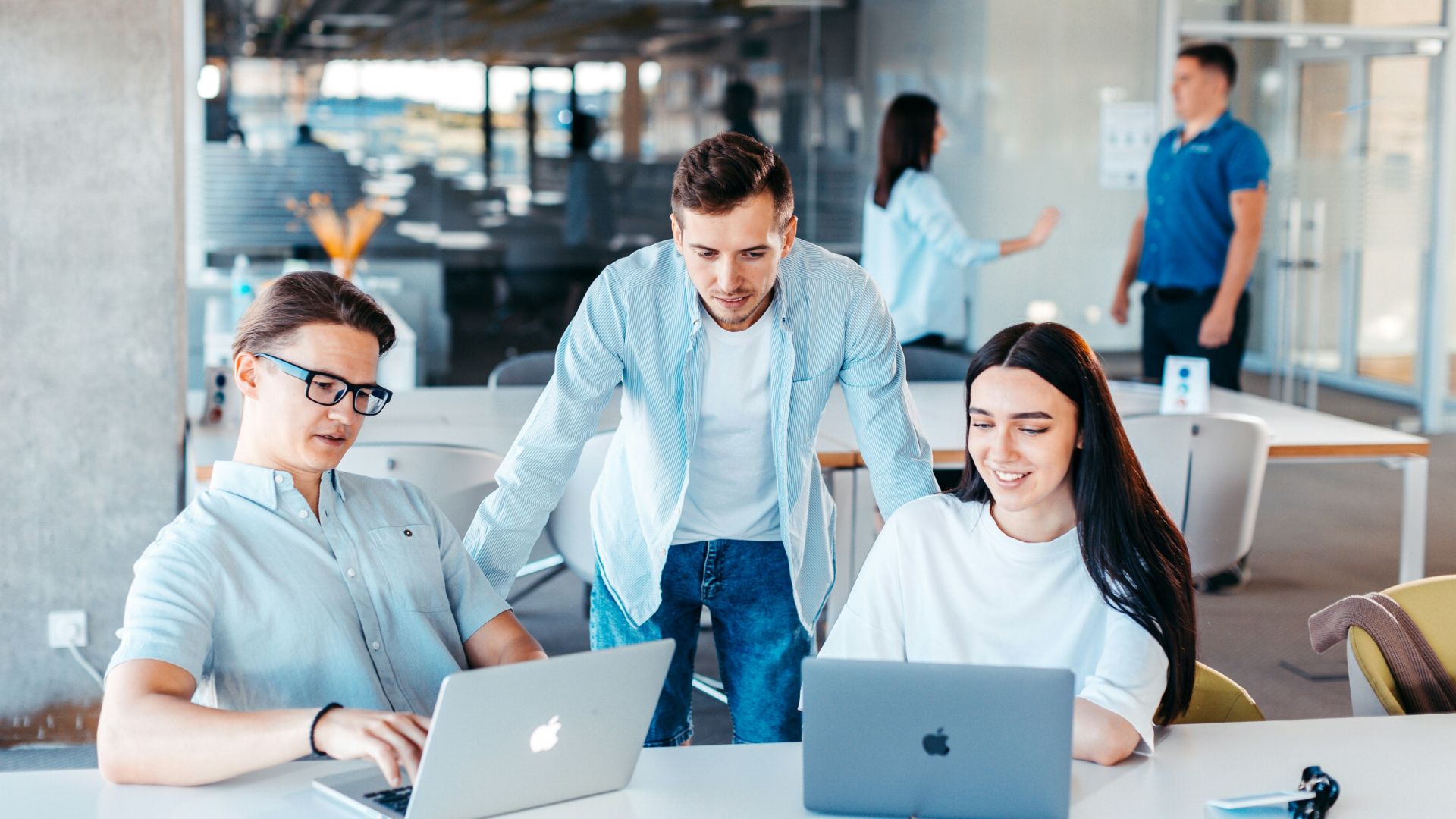 a group of people sitting around a table with laptops