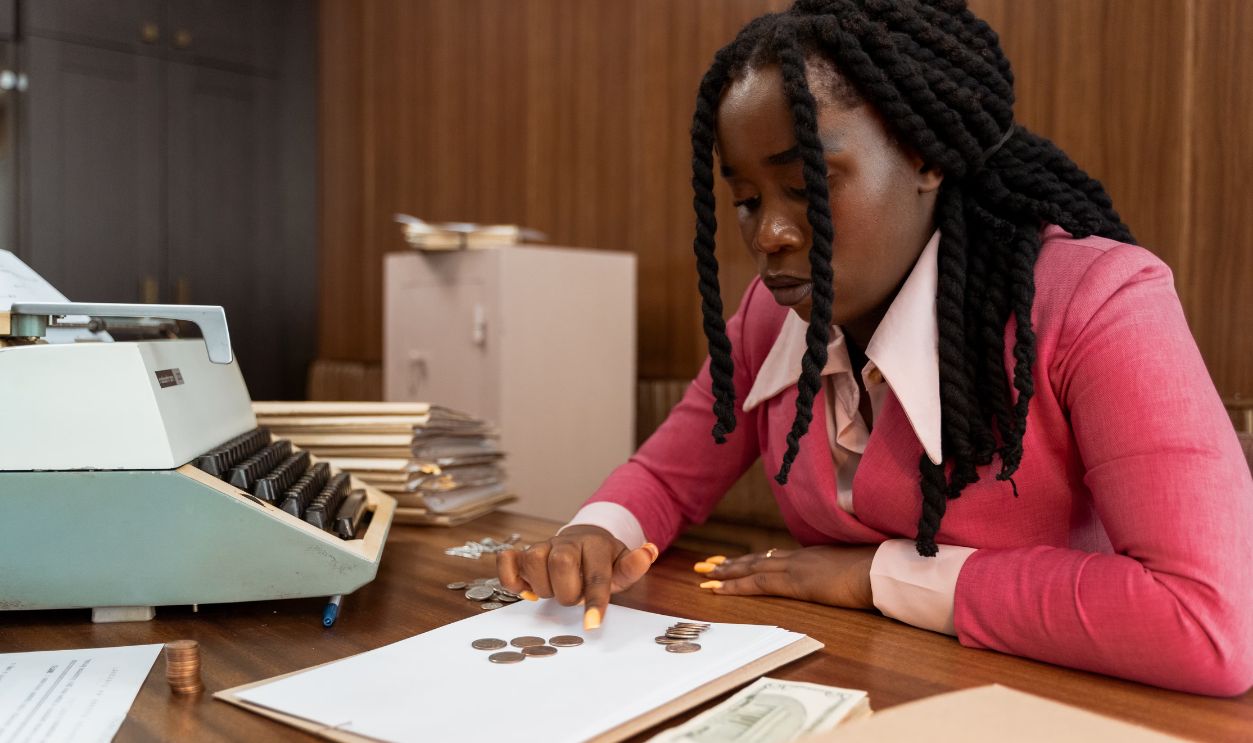 A businesswoman in vintage attire counts coins in a retro office setting