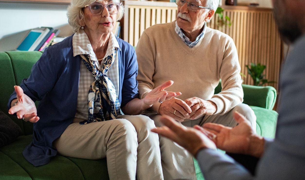 Elderly couple having a serious conversation with a therapist at home
