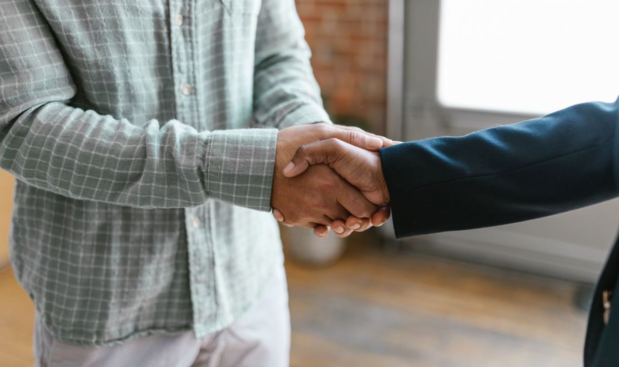 Close-up of two business professionals shaking hands in a modern office environment.