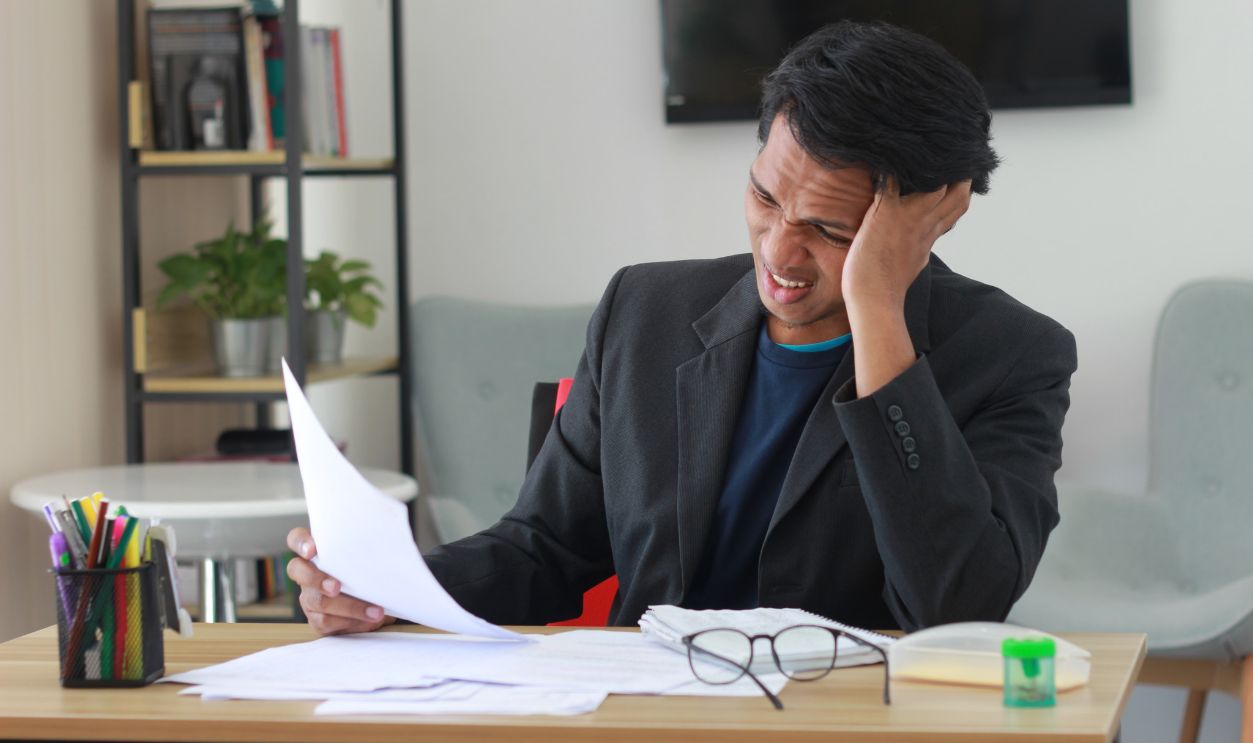 A businessman in an office experiencing stress while reviewing documents