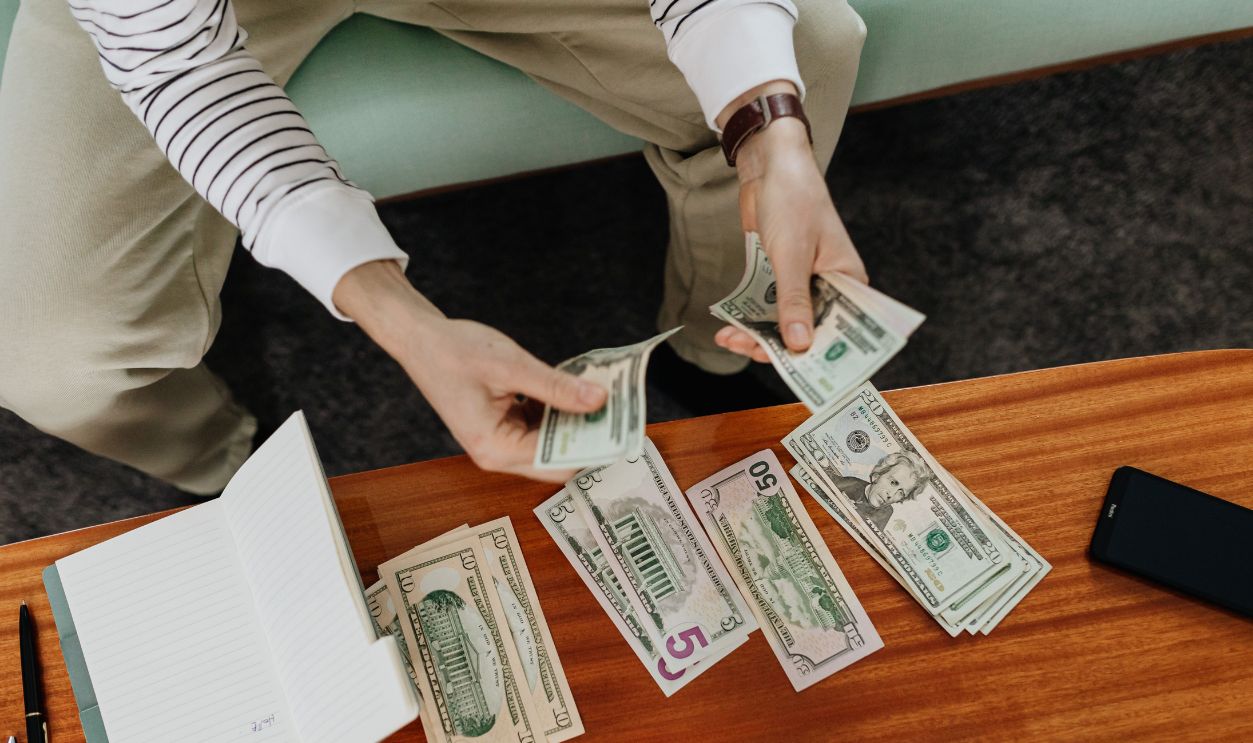 A person sitting and counting various US dollar bills