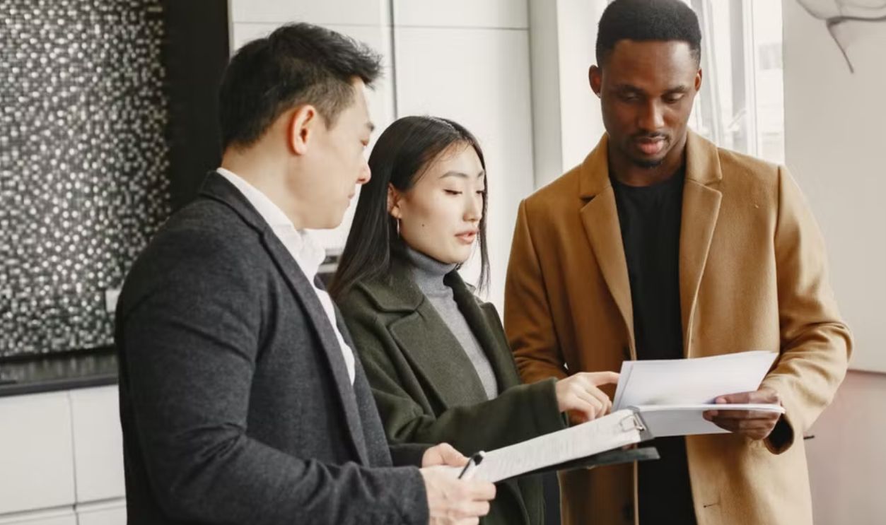 A diverse group of adults collaborates indoors on a project, examining documents and planning