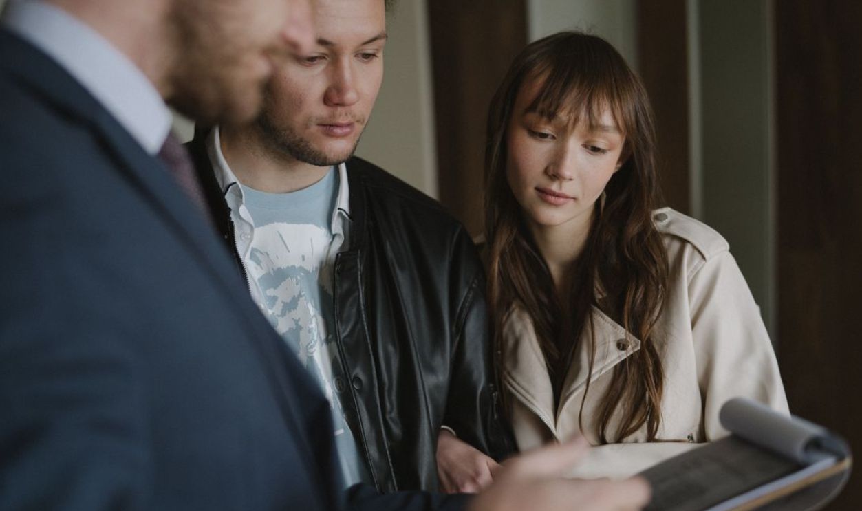 A couple discusses home buying details with a realtor inside a modern apartment