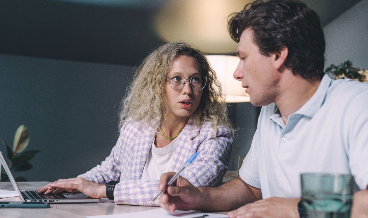 Two coworkers engaged in a focused discussion at a modern office