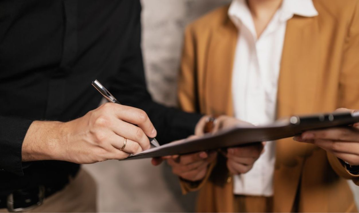 Close-up of two professionals signing a document indoors, focus on hands and pen