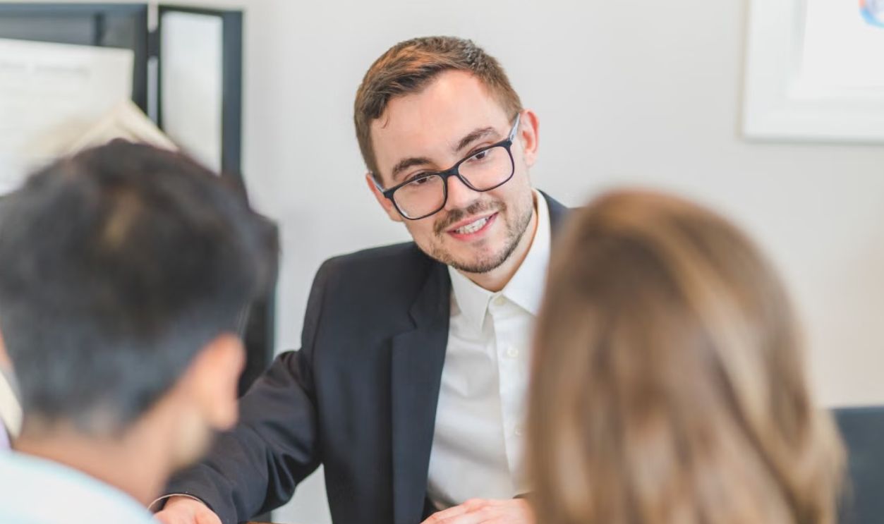 Smiling businessman in a suit and eyeglasses during a team discussion