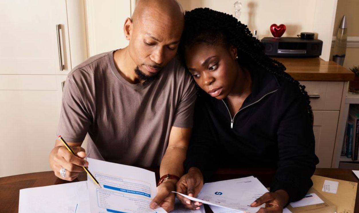 A couple sitting at a table reviewing financial documents, highlighting domestic budgeting