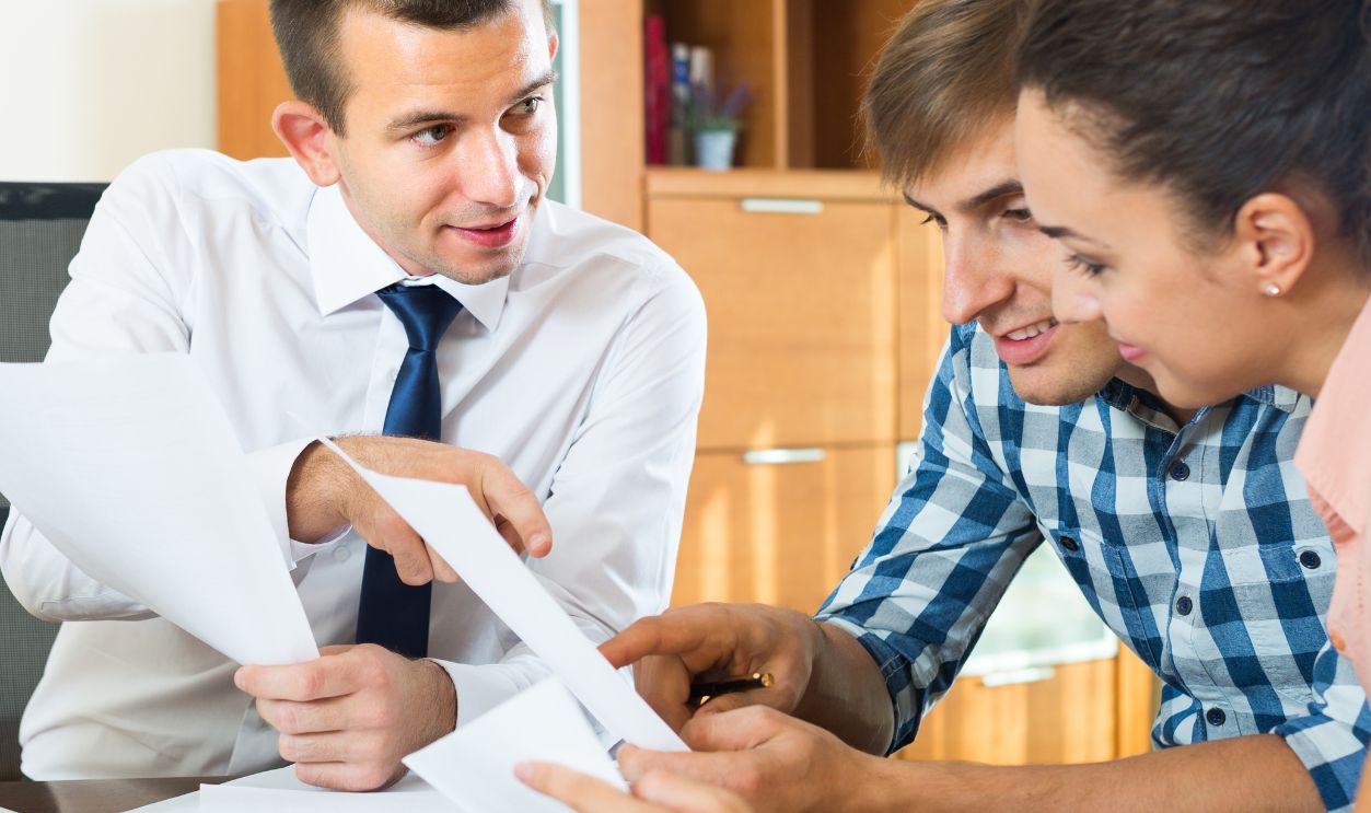 Male agent consulting young couple about offer details in office